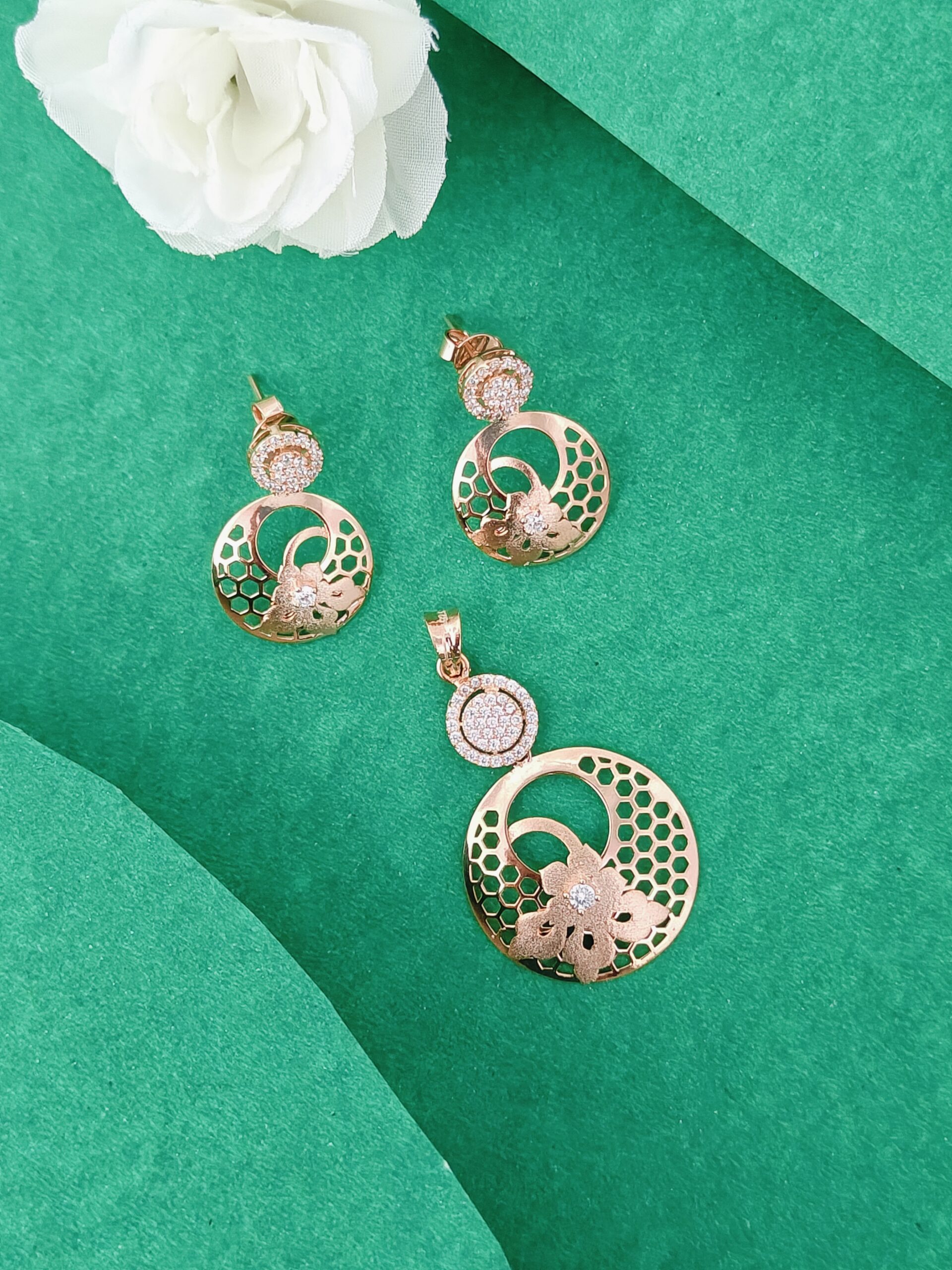 Gold jewelry set with pendant and earrings on a green background